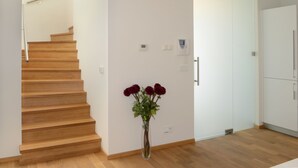 A modern interior with a wooden staircase, a white door, and a vase with flowers. - Apartmány Eden (Luhacovice)
