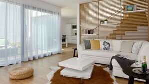 A modern living room with a white sofa, a coffee table, and a wooden slatted wall. - Apartmány Eden (Luhacovice)