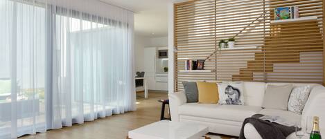 A modern living room with a white sofa, a coffee table, and a wooden slatted wall.