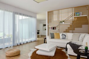 Una sala de estar moderna con un sofá blanco, una mesita de centro y un revestimiento de pared de listones de madera.