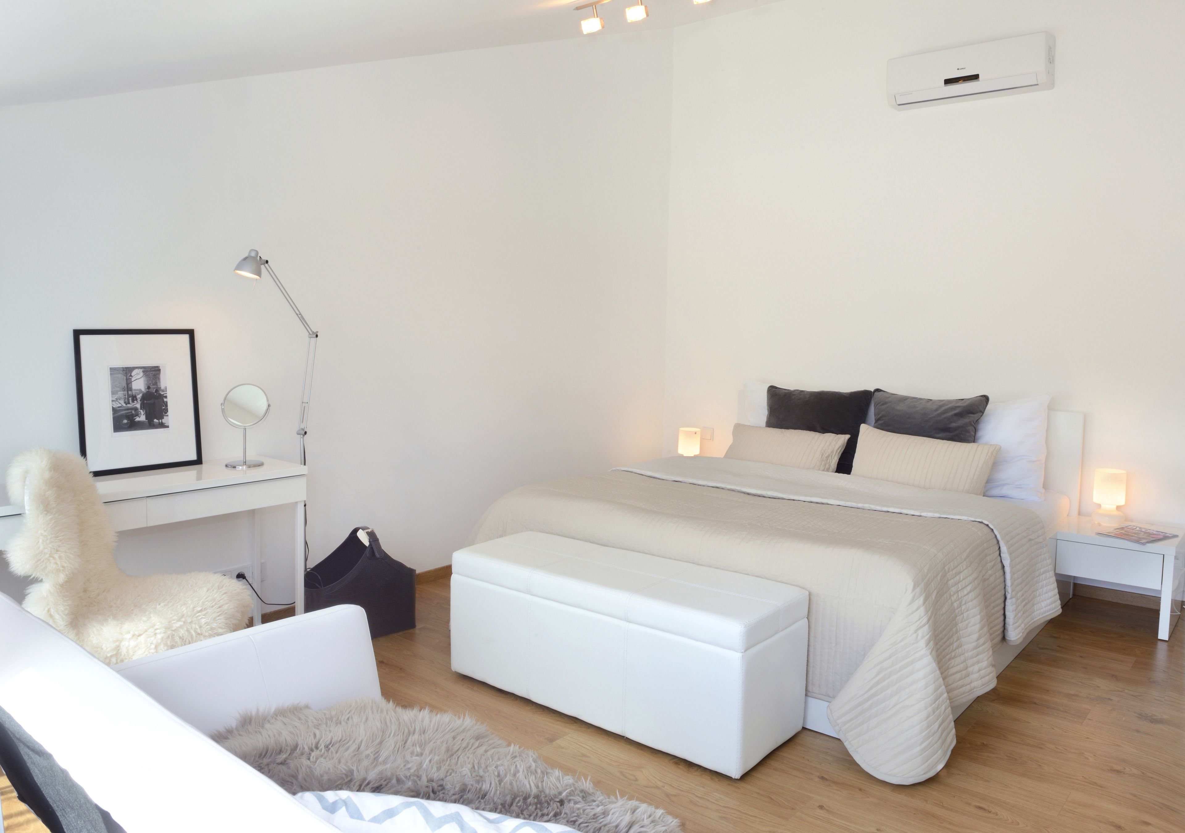 A modern bedroom with a bed, bedside tables, a desk, a chair, and a large window.