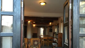 A cozy interior with wooden furniture, a fireplace, and a bookshelf. - Krishna House (Bhaktapur)