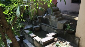 A stone staircase leading to a small pond with potted plants. - Krishna House (Bhaktapur)