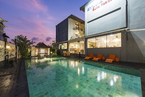 Un hotel moderno con piscina, zona de estar exterior y restaurante-bar.