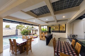 A spacious indoor area with a pool, multiple dining tables, and chairs. - Sylvia Bali Suite Residence (Denpasar)