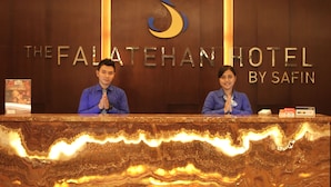 A reception desk at The Falatehan Hotel by Safin with two staff members standing behind it. - The Falatehan Hotel (Jakarta)