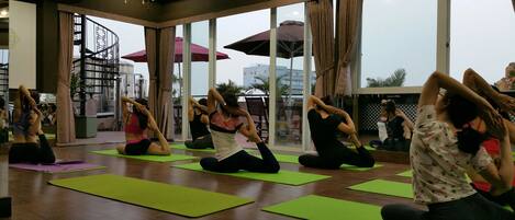 A yoga class in a spacious room with large windows, green mats, and a modern interior design.