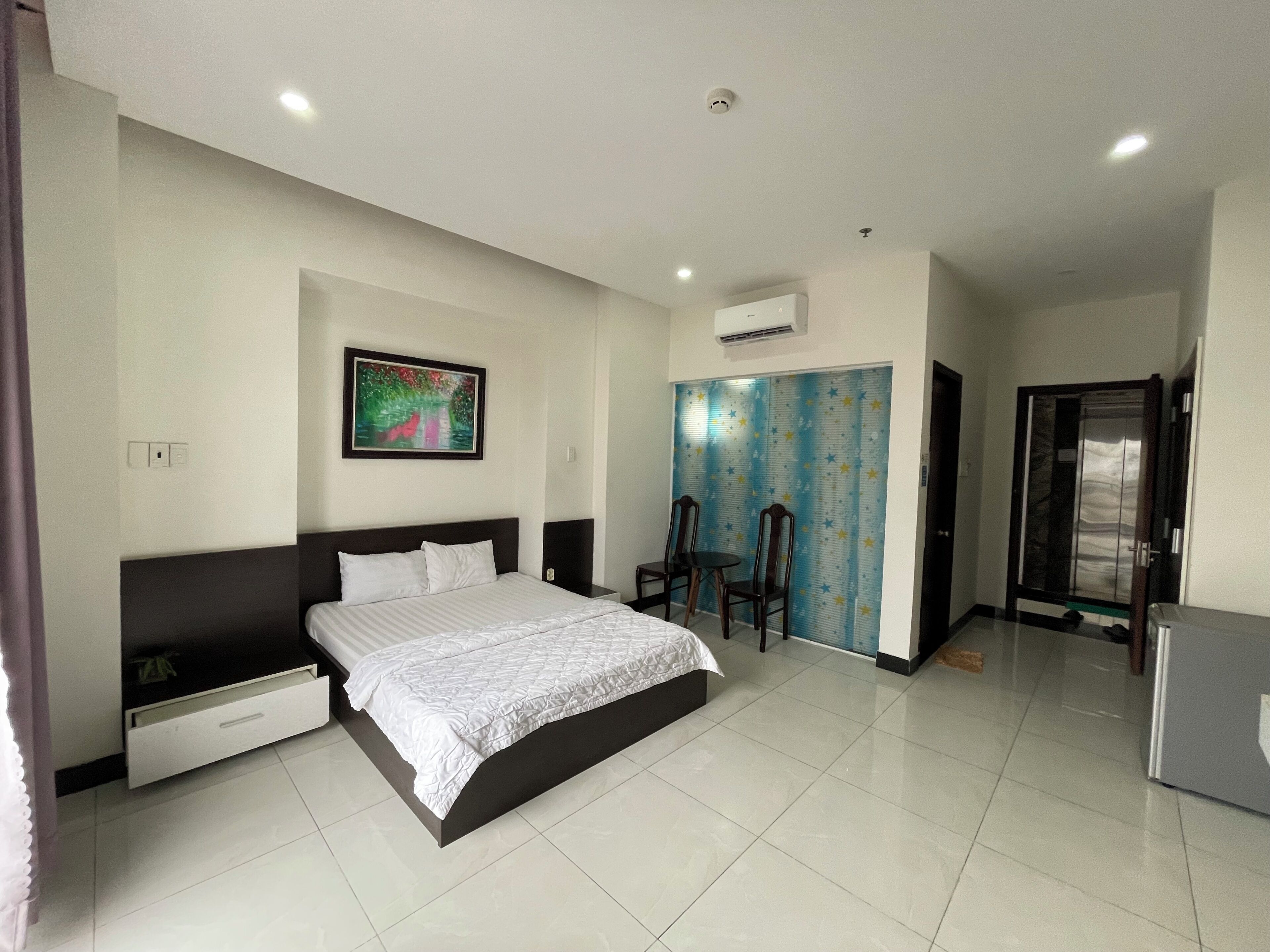 A modern bedroom with a bed, a nightstand, a chair, a wardrobe, and a door.
