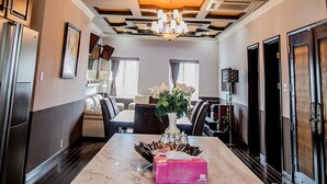 Een moderne keuken met een marmeren eiland, een kroonluchter en een eetgedeelte met uitzicht.