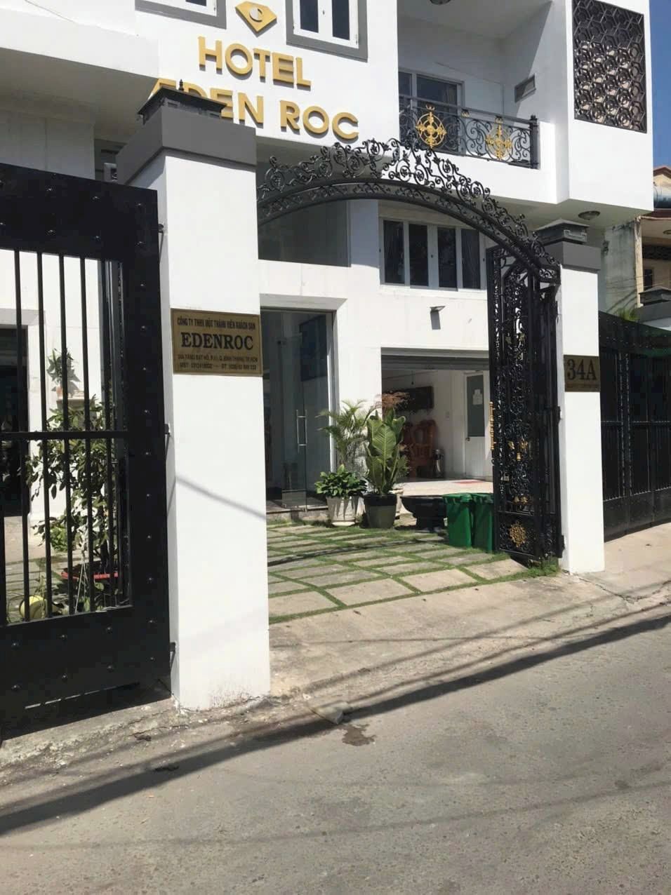 Entrada de hotel con camino de entrada porticado, plantas en macetas y un letrero con el nombre del hotel.