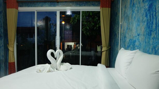 A hotel room with a bed, white pillows, and a swan-shaped towel arrangement. - Samui Poshtel (Koh Samui)
