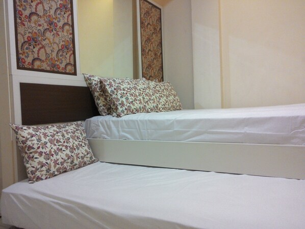A double bed with floral-patterned pillows and a plain white bedspread.