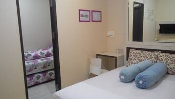 A bedroom with a bed, a desk, a chair, and a mirror.