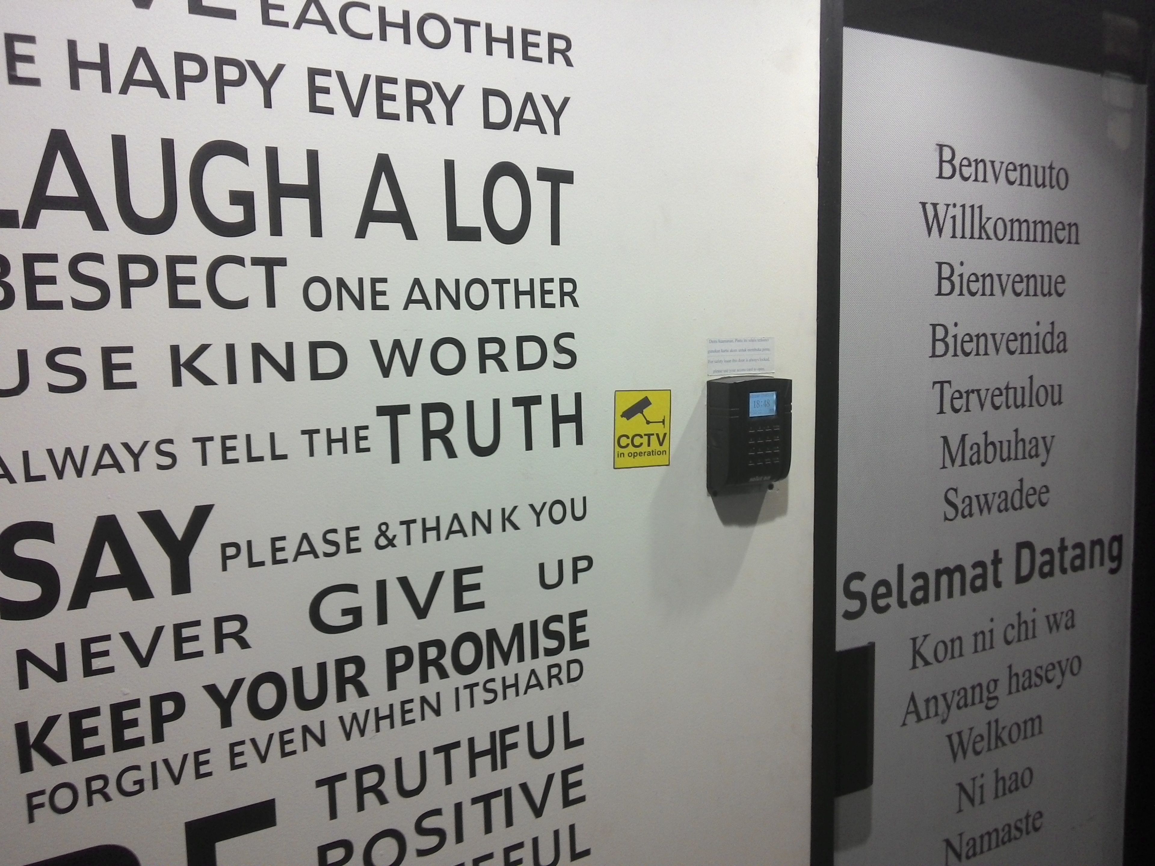 A wall with motivational phrases and a CCTV sign.