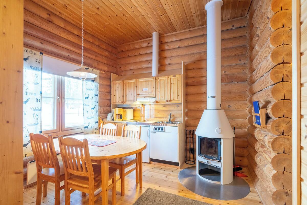 Interno di una baita in legno con zona pranzo, angolo cottura e stufa a legna.