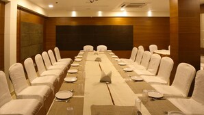 A conference room with a long table, chairs, and a projector screen. - Hotel Park N (Penumuluru)