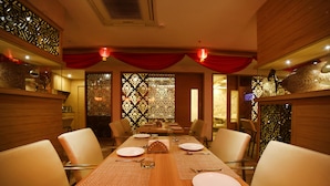 A dining area with a long wooden table set for six, surrounded by chairs. - Hotel Park N (Penumuluru)