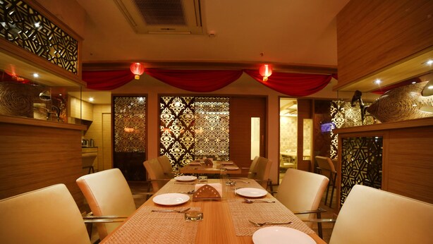 A dining area with a long wooden table set for six, surrounded by chairs. - Hotel Park N (Penumuluru)