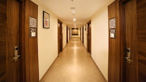A hotel hallway with wooden doors numbered 201 and 208, a tiled floor, and recessed lighting. - Hotel Park N (Penumuluru)
