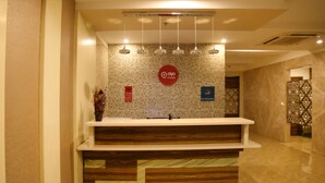 A reception desk with a 'No Smoking' sign, a CCTV warning sign, and a 'Q Rooms' logo. - Hotel Park N (Penumuluru)