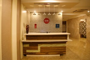 A reception desk with a 'No Smoking' sign, a CCTV warning sign, and a 'Q Rooms' logo. - Hotel Park N (Penumuluru)