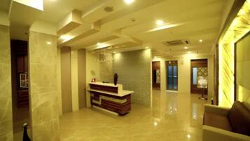 A spacious lobby with a reception desk, polished marble floors, and a modern ceiling design.