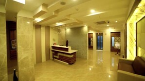 A spacious lobby with a reception desk, polished marble floors, and a modern ceiling design. - Hotel Park N (Penumuluru)