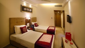 A hotel room with two beds, a ceiling fan, a TV, and a red sign on the nightstand. - Hotel Park N (Penumuluru)