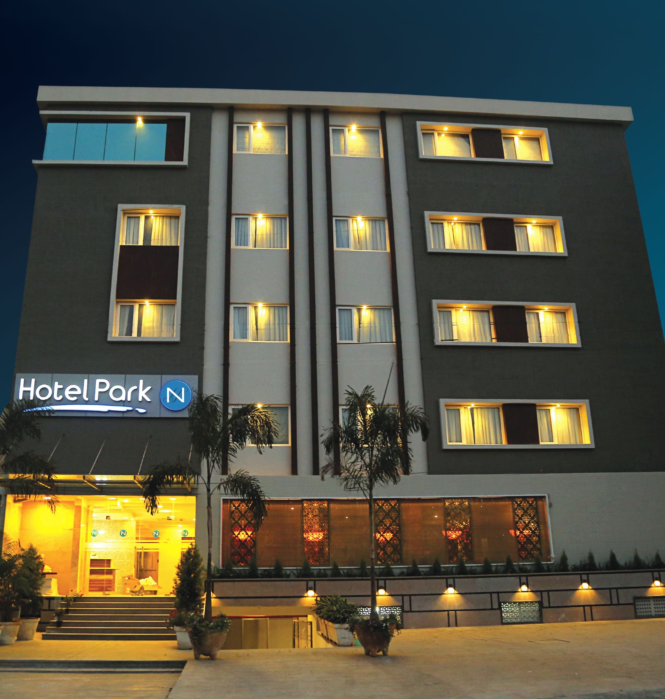 A multi-story hotel with a modern facade, illuminated windows, and a sign reading "Hotel Park".