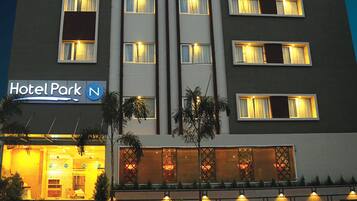 A multi-story hotel with a modern facade, illuminated windows, and a sign reading "Hotel Park".