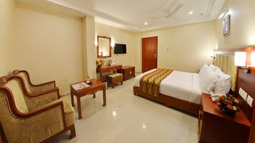 A hotel room with a bed, a desk, a chair, a television, and a bathroom.