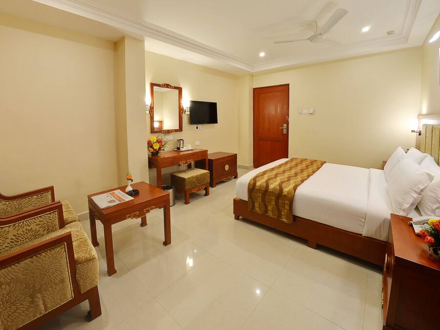 A hotel room with a bed, a desk, a chair, a television, and a bathroom.