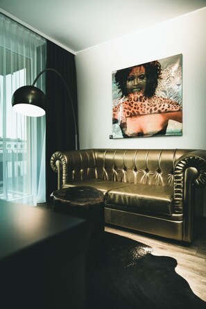 Una sala de estar moderna con un sofá de cuero, una lámpara de pie y una obra de arte con estampado de leopardo en la pared.