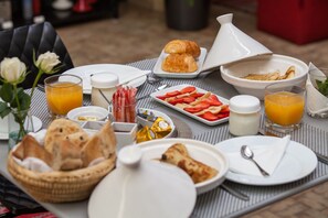 A breakfast setting with croissants, strawberries, orange juice, and bread on a table. - Riad Shanima & Spa (Marrakech)