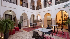 A spacious courtyard with multiple arches, a dining area with tables and chairs, and potted plants. - Riad Shanima & Spa (Marrakech)