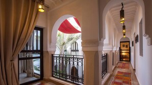 A corridor with arches, a patterned carpet, and a view through an arch to a palm tree. - Riad Shanima & Spa (Marrakech)