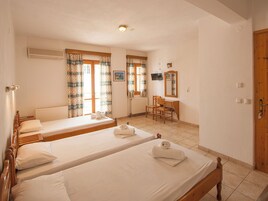 Una habitación con dos camas individuales, un escritorio de madera, una silla, un radiador y un televisor en la pared.