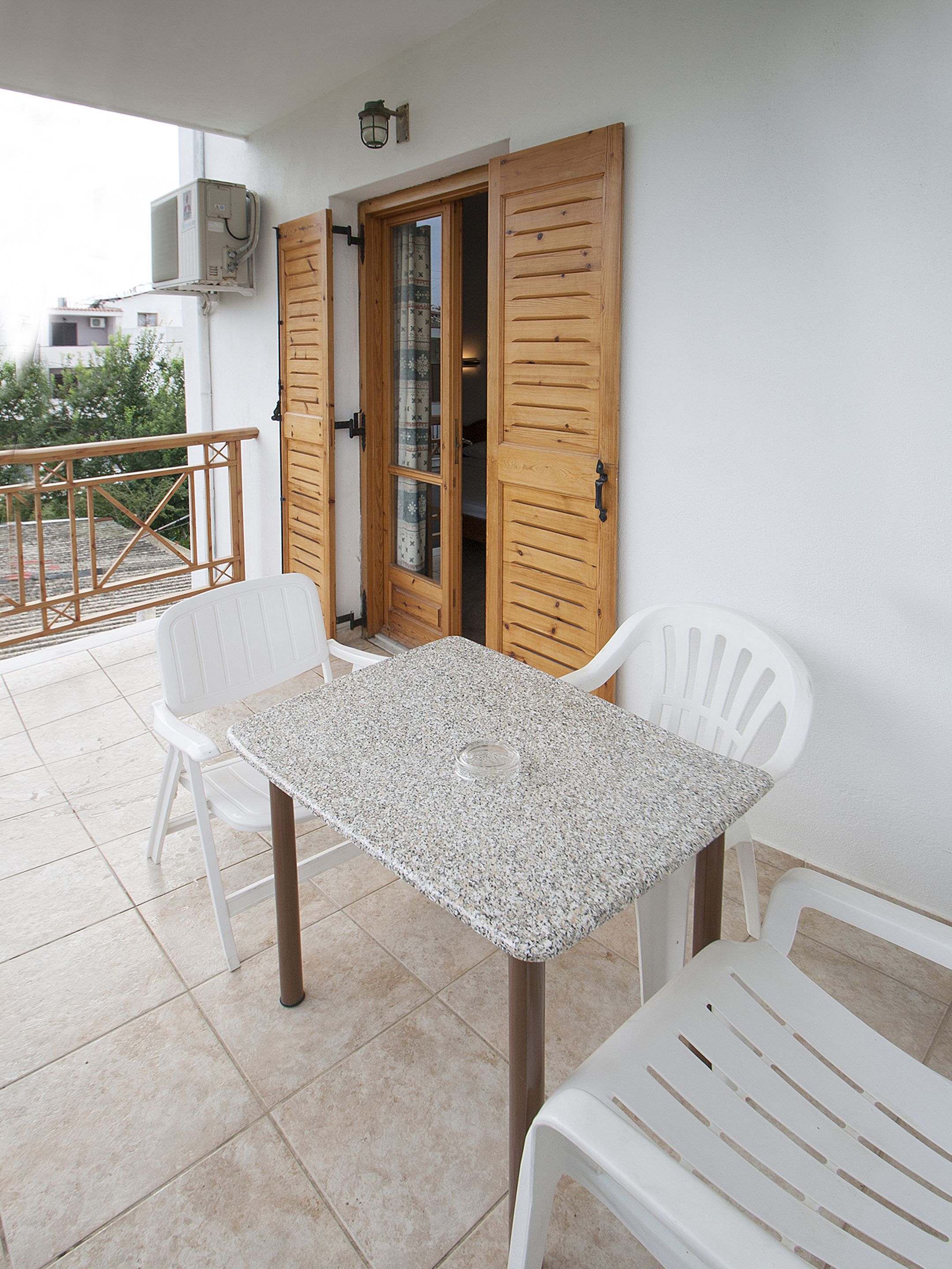 A patio with a table and chairs, a wooden door, and an air conditioning unit.