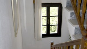 Una escalera con barandal de madera y una pared blanca con un ventanal.