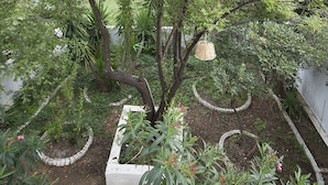 Un jardín con un árbol central rodeado de macetas blancas y un sendero curvo.