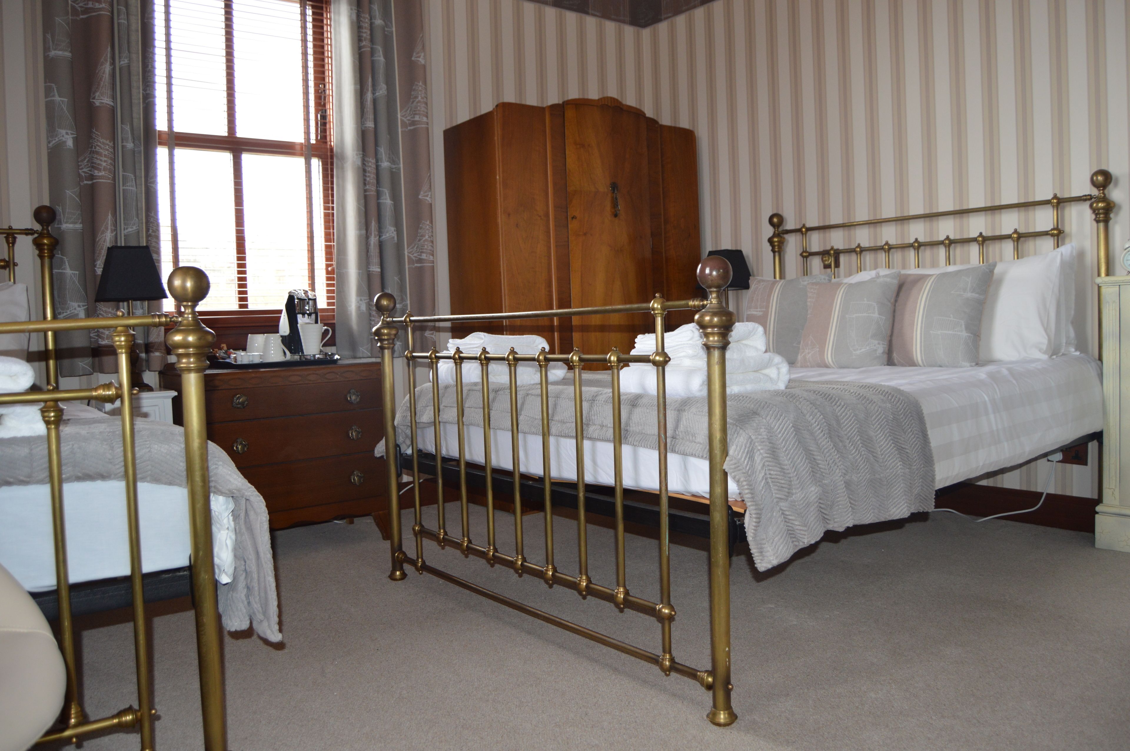 A bedroom with a four-poster bed, a wooden wardrobe, and a desk with a lamp.