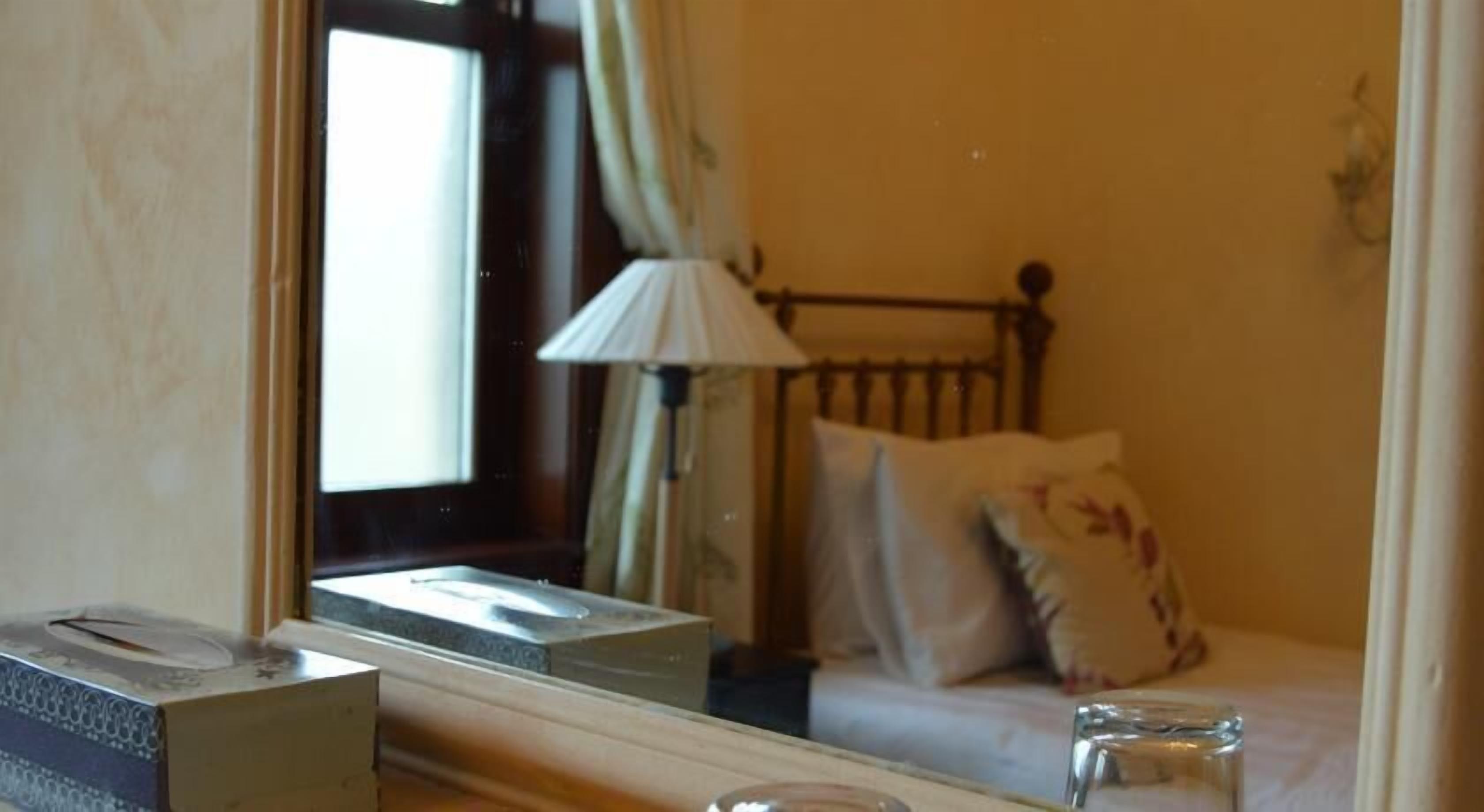 A hotel room with a bed, a lamp, and a window.