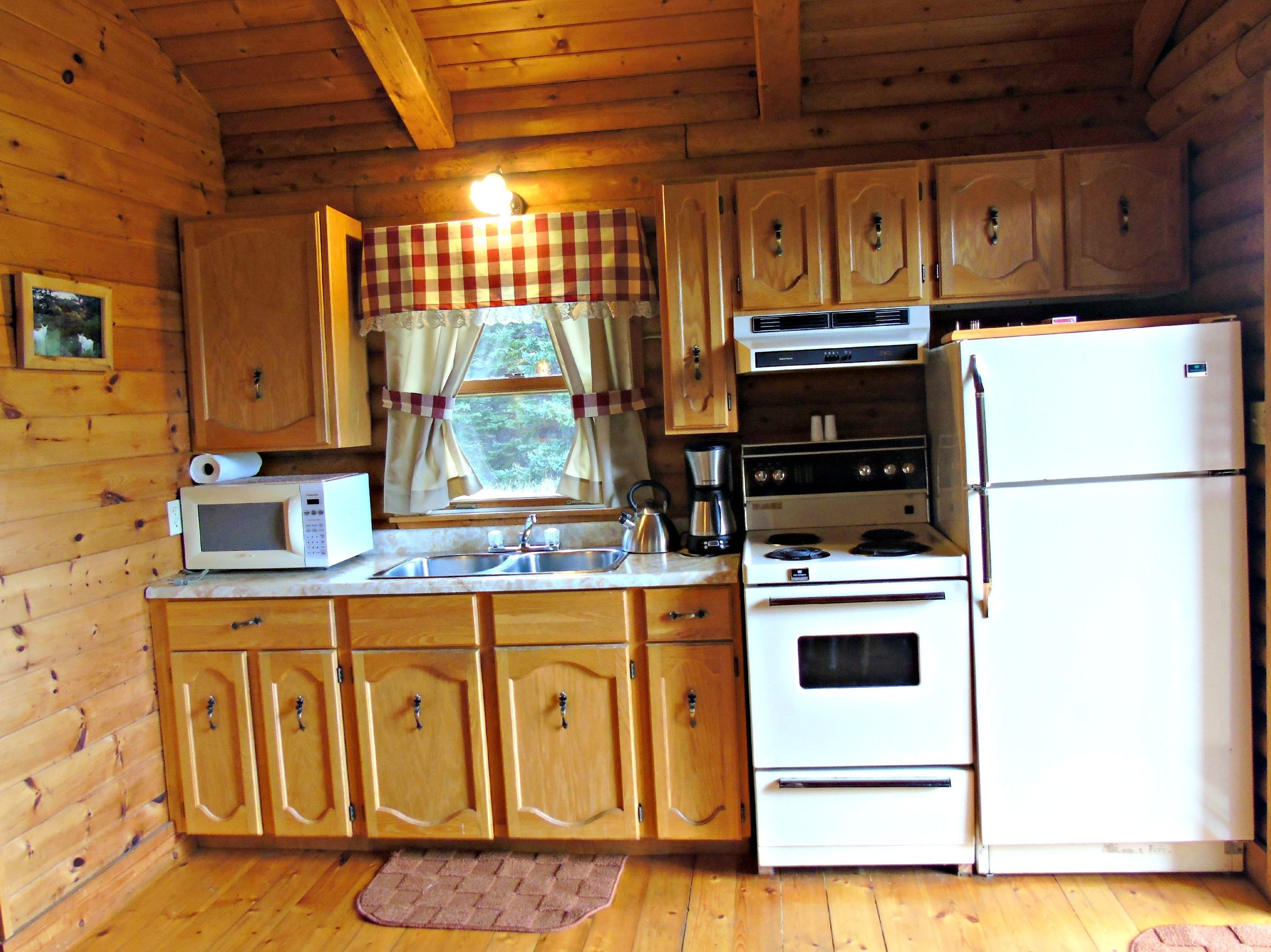 A compact kitchen with wooden cabinets, a microwave, stove, and refrigerator.