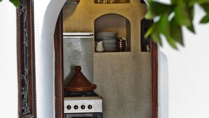 A compact kitchen with a stove, oven, and shelves above. - Riad Porte Royale (Marrakech)