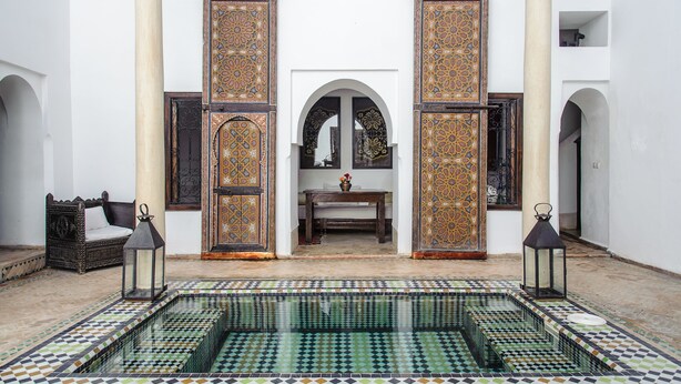 A courtyard with a tiled swimming pool, ornate doors, and a bench. - Riad Porte Royale (Marrakech)
