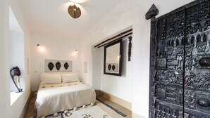 A bedroom with a bed, a large mirror, and a decorative door. - Riad Porte Royale (Marrakech)