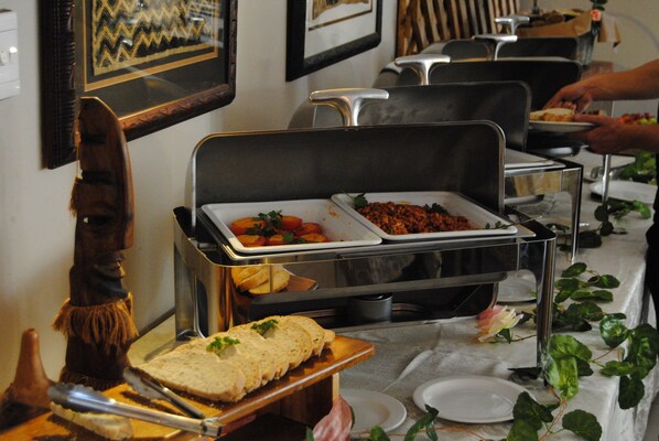 Una mesa de buffet con diferentes alimentos y una figura decorativa de madera.