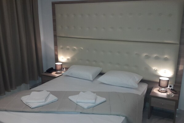 A hotel room with a large bed, two bedside tables, and a headboard with a tufted design.