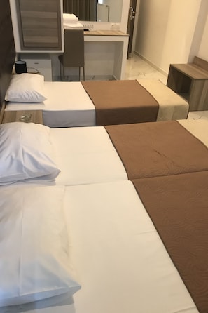 A hotel room with two beds, a desk, and a chair.