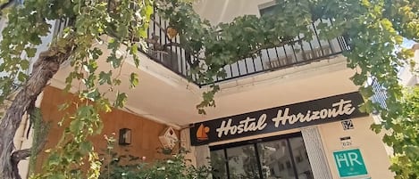 A building with a sign reading "Hostal Horizonte" and a balcony with a railing.